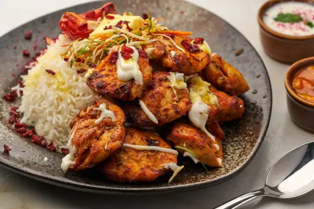 Photo of Joojeh Kebab with rice and raita served in a dish isolated on grey background side view of fastfood