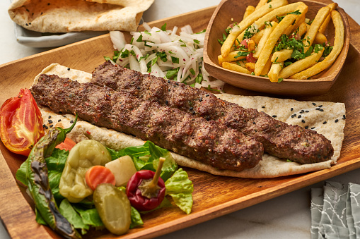 Lamb Kebab with fries, pita bread and lime served in a dish isolated on grey background side view of fastfood