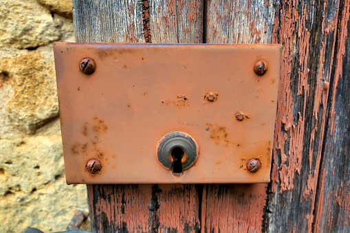 Close up of a rusty lock fitted to a shabby French shutter