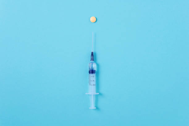 istock Syringe with injection  yellow pill. Blue background. concept. 1413070819