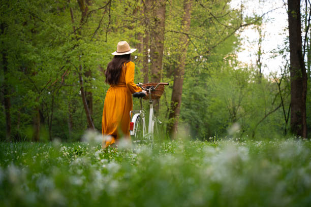 istock Rear view of woman walking with bicycle while exploring in forest 1413072307