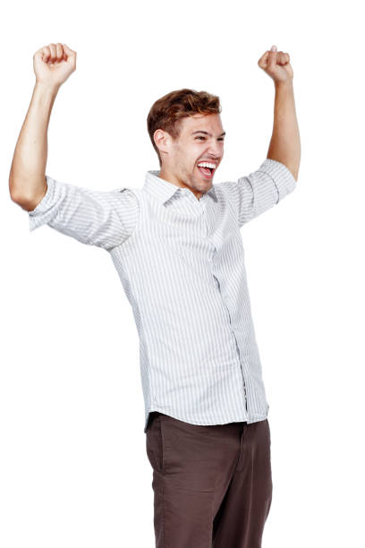 istock Handsome young man posing against a white background in studio. Excited male wearing a stripped shirt posing with his arms raised, celebrating and cheering a win or achievement. Success and victory 1413072858