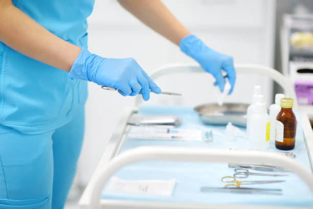 Nurse laying out medical instruments on the table in the operating room stock photo