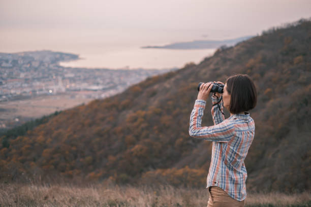 istock Young woman in the mountains looks through binoculars. 1413073978