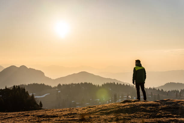 istock Man watching sunrise while standing on top of mountain 1413075054