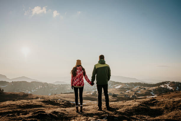 istock Couple holding each other's hands while standing on mountain top 1413075204