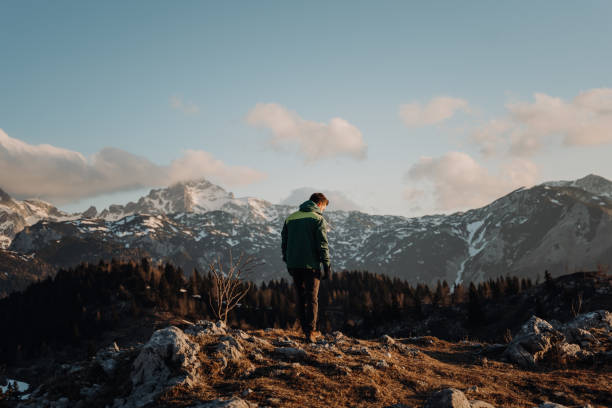 istock Man standing on rocky hill against snowcapped mountains 1413075233