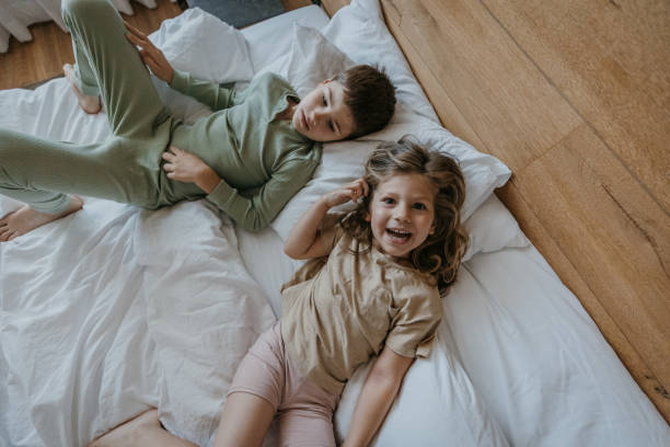 istock Little brother and sister lying on bed and enjoying 1413075476