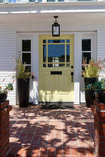 Brick patio leads to yellow Dutch door of bungalow