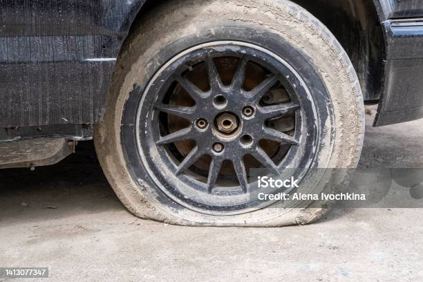 Closeup Of A Damaged Flat Tire Of A Car On The Road Old Wheel Car Dirty And Flat Tires Car Tire Puncture Stock Photo - Download Image Now