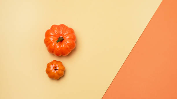 Two Fake Pumpkins on Warm Yellow and Orange Background Autumn Halloween Concept Top View Copy Space