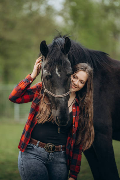 istock Smiling affectionate woman embracing horse on grassy field 1413079045