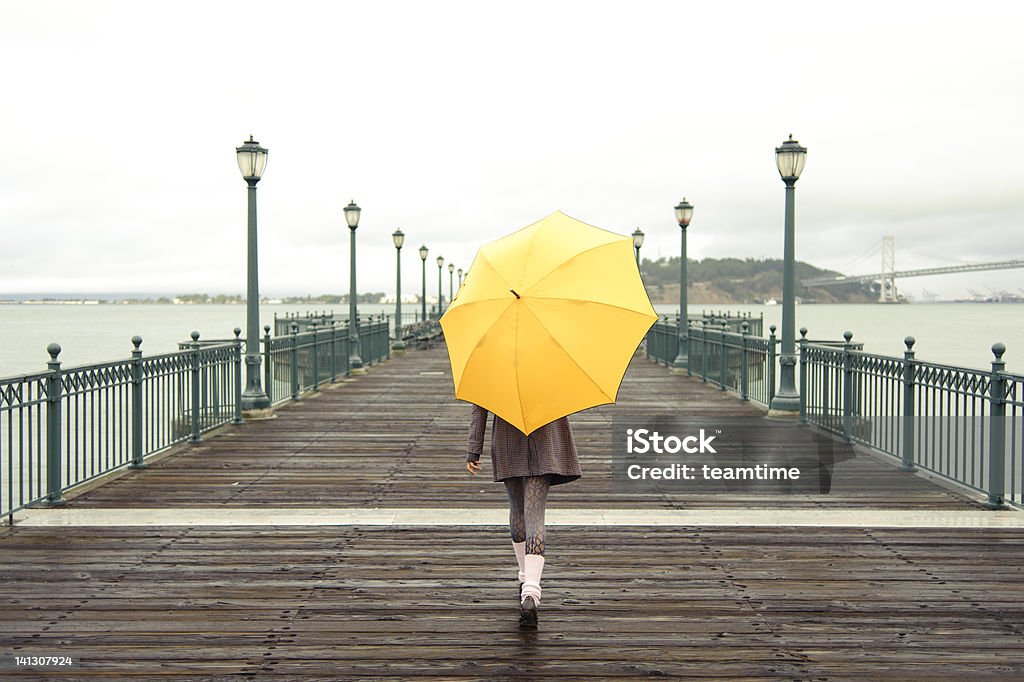 A girl with an umbrella on a San Francisco pier Pretty African American girl walking with umbrella on the pier in San Francisco Umbrella Stock Photo