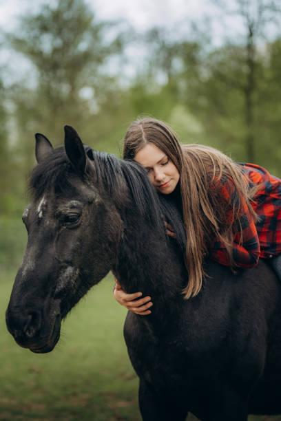 istock Young woman embracing horse while riding in ranch against trees 1413079485