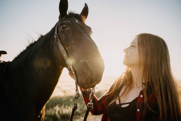 istock Smiling woman looking at horse while standing against sky 1413079556
