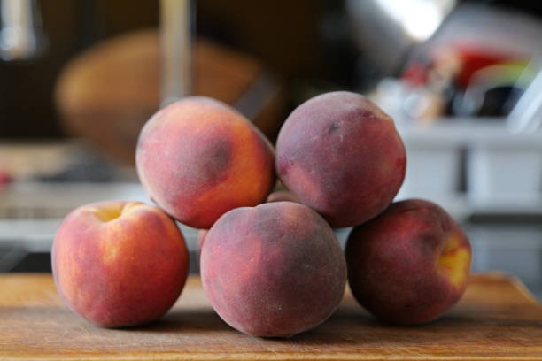 istock Five peaches on a wooden cutting board 1413080724