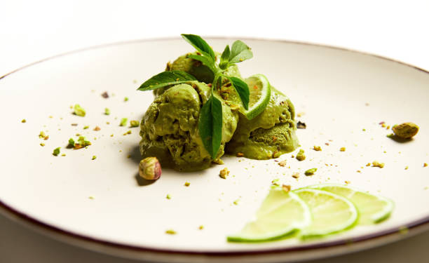 Refreshing ice cream sorbet topped with juicy lime, pistachio, green lemon basil leaf. Food still life isolated on white