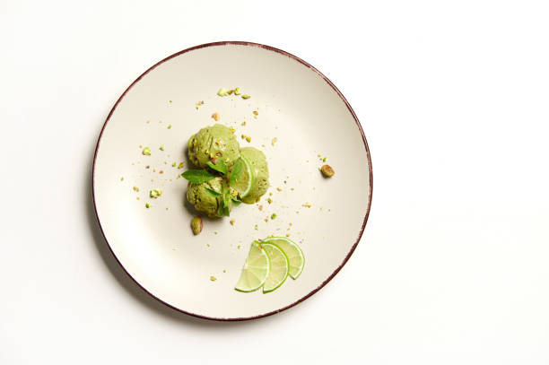 Flat lay. Three balls of pistachio and lime ice cream sorbet on a plate, isolated on white background with copy ad space