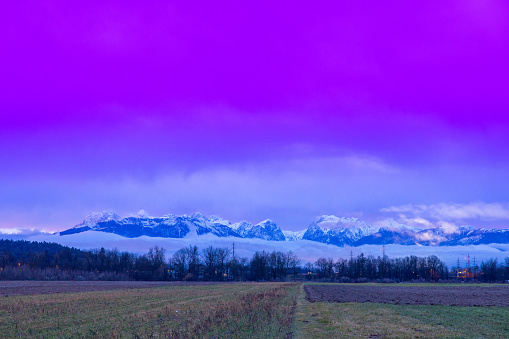 Beautiful view of landscape and snowcapped mountains against cloudy sky during winter
