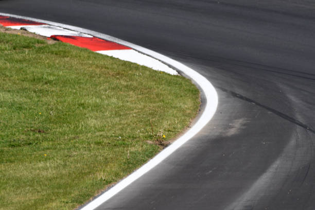 istock A left corner on an asphalt grey race track highlighted by red and white chevrons, clear dark grey skid marks indented on the race track 1413084602