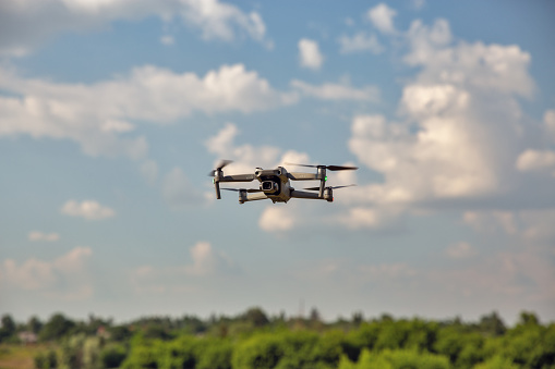Kyiv, Ukraine - July 11, 2021: Modern drone DJI Mavic Air 2S flying in the sky closeup. DJI is a Chinese technology company manufactures commercial drones for aerial photography and videography.