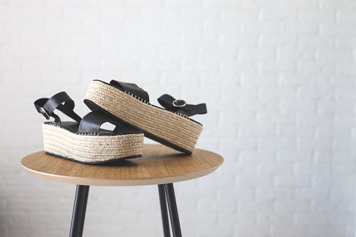 Stylish wicker women's sandals on a white background wooden table