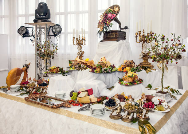 Buffet table with meat snacks, baked pigs in dough, cheese, turkey with fruit, decorated with candelabra and gramophone.
