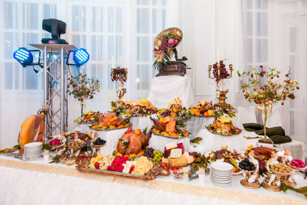 Buffet table with meat snacks, baked pigs in dough, cheese, turkey with fruit, decorated with candelabra and gramophone.