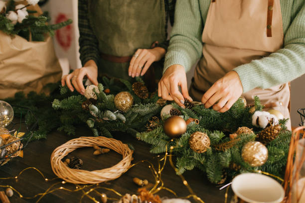 istock Two millennial women making Christmas wreath using pine branches and festive decorations. Small business 1413088177