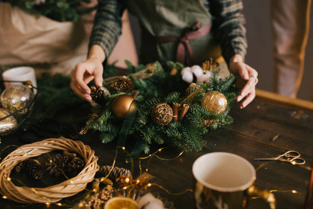 istock Millennial woman making Christmas wreath using pine branches and festive decorations in workshop. Small business 1413088186