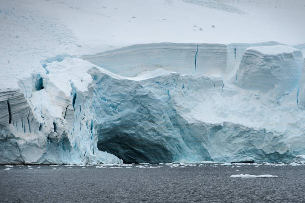 istock Ice cave undermines the glacier edge causing it to calf in Antarctica 1413088894