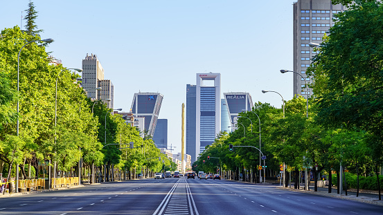 Madrid, Spain - July 30, 2022: Paseo de la Castellana in Madrid with tall company headquarters buildings and trees on the sides of the wide avenue