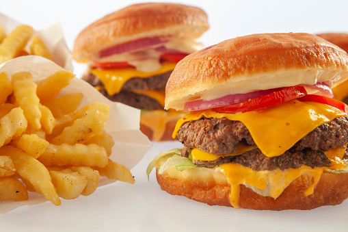 Brioche donut double decker beef cheese burger with queso sauce with another burger in the background.