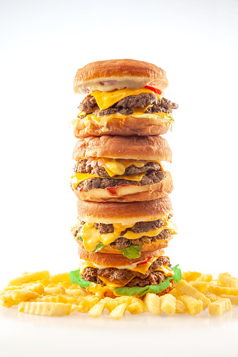 Gourmet brioche donut burgers tower stacked on top of one another with crinkle French potato fries.