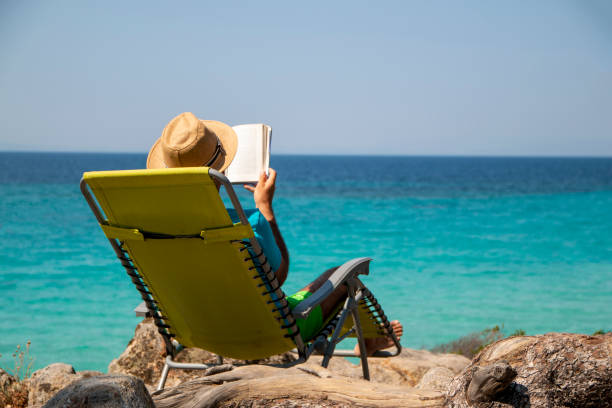 istock Man is reading a book next to the see 1413090093