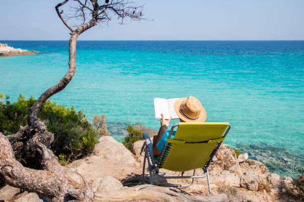 istock Man is reading a book next to the see 1413090097