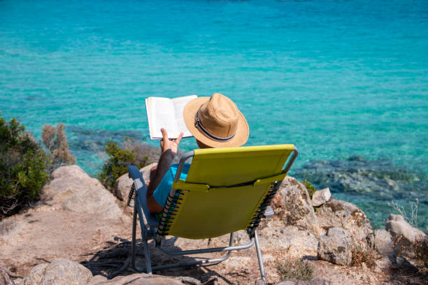 istock Man is reading a book next to the see 1413090098