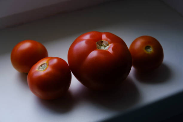 a red ripe eco-friendly tomatoes on the windowsill on a sunny morning