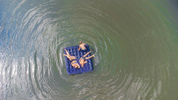 niños con mamá flotan en un colchón inflable en el río - child inflatable raft lake family fotografías e imágenes de stock