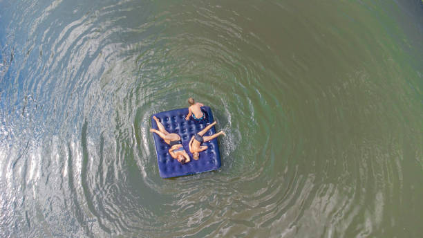 crianças com a mãe flutuam em um colchão inflável no rio - child inflatable raft lake family - fotografias e filmes do acervo