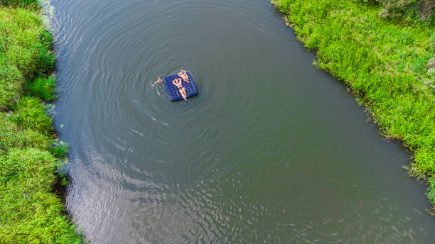 niños con mamá flotan en un colchón inflable en el río - child inflatable raft lake family fotografías e imágenes de stock