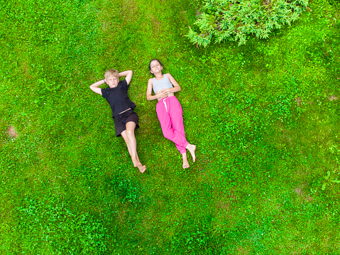 Beautiful happy relaxed woman lying in a green, yellow chamomile field. Retreat, leisure, energizing concept
