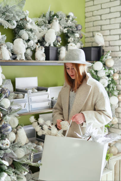 istock Girl in hat choosing Christmas decoration in store, silver colored 1413097929