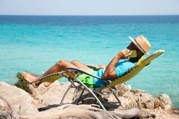 istock Mature man talking by mobile phone on beach. 1413099519
