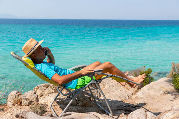 istock Mature man talking by mobile phone on beach. 1413099660