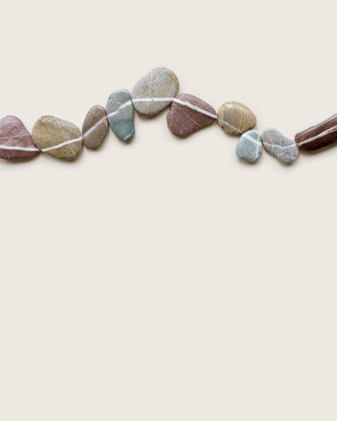istock Aesthetic minimal flat lay sea pebble stones with white line, beige background. Composition from natural colored stone on the same level. Balance or harmony concept, horizontal row rocks. 1413104291