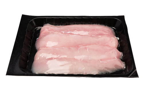 Raw rabbit breast meat in a black plastic container. Isolate.