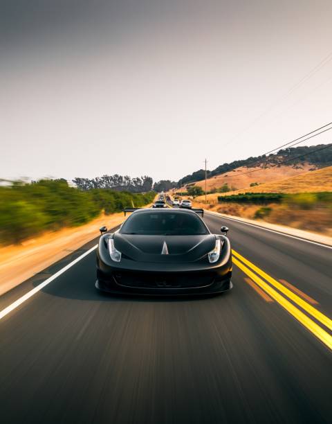 LA, CA, USA April 4, 2022 Ferrari 458 widebody in black driving on the road with trees on both sides of the road
