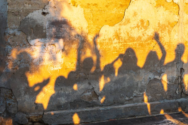 istock Shadows of dancing people on an old stone wall at sunset time. 1413117313