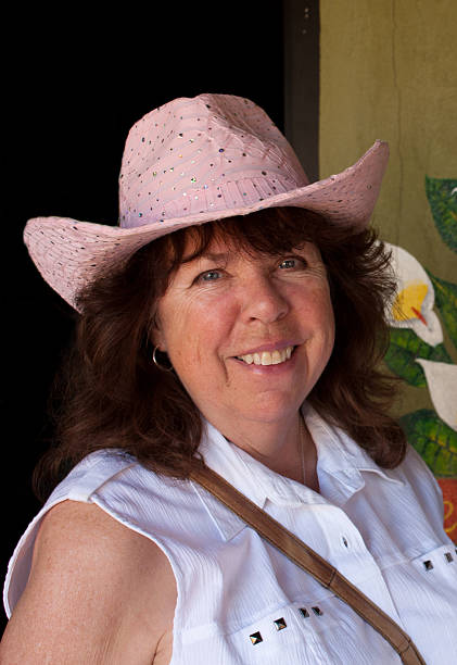 Pink Hat Lady Close up of a friendly attractive mature woman in a pink cowboy hat smiling towards the camera. yuma photos stock pictures, royalty-free photos & images